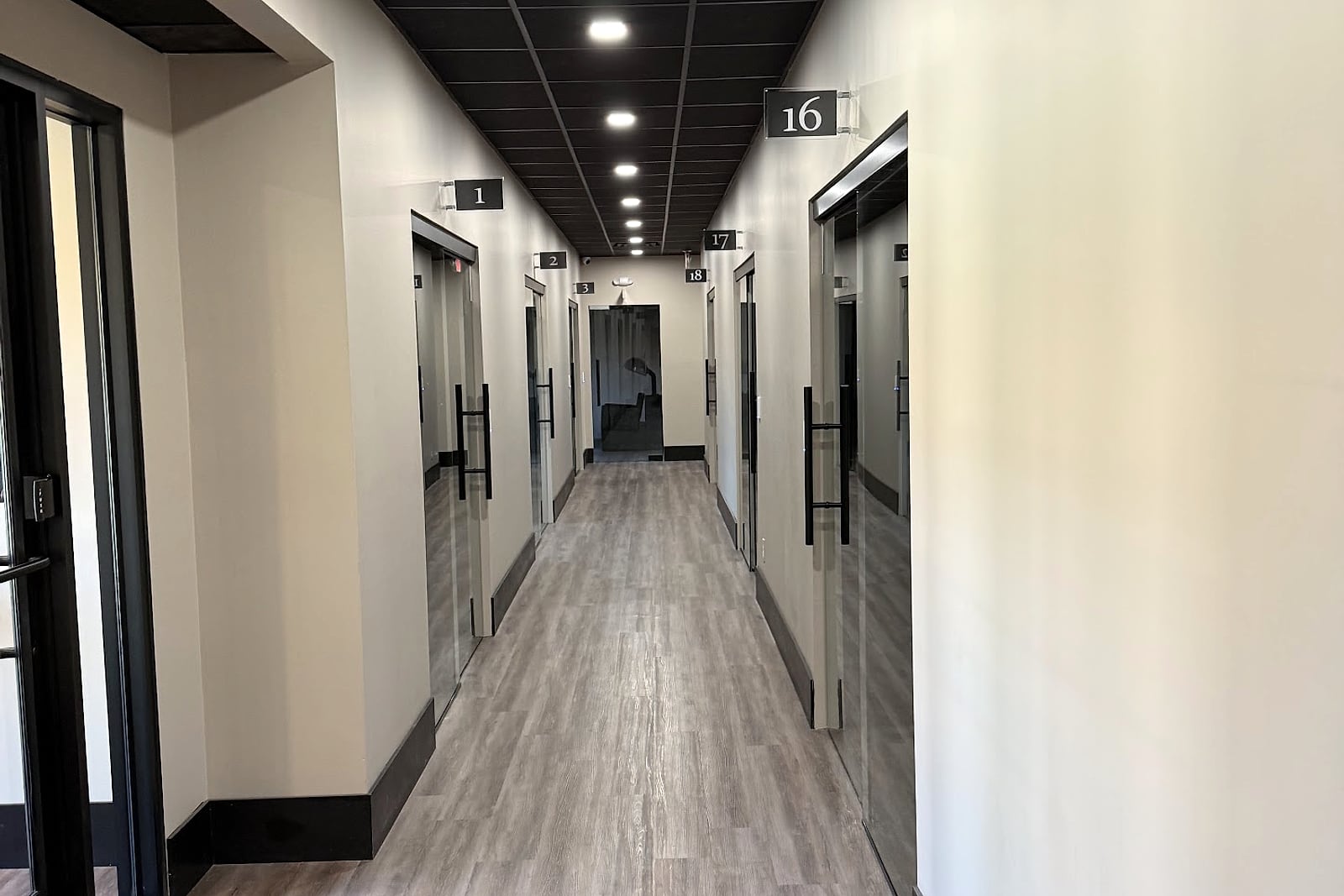 Finished commercial hallway with access-controlled glass office doors.