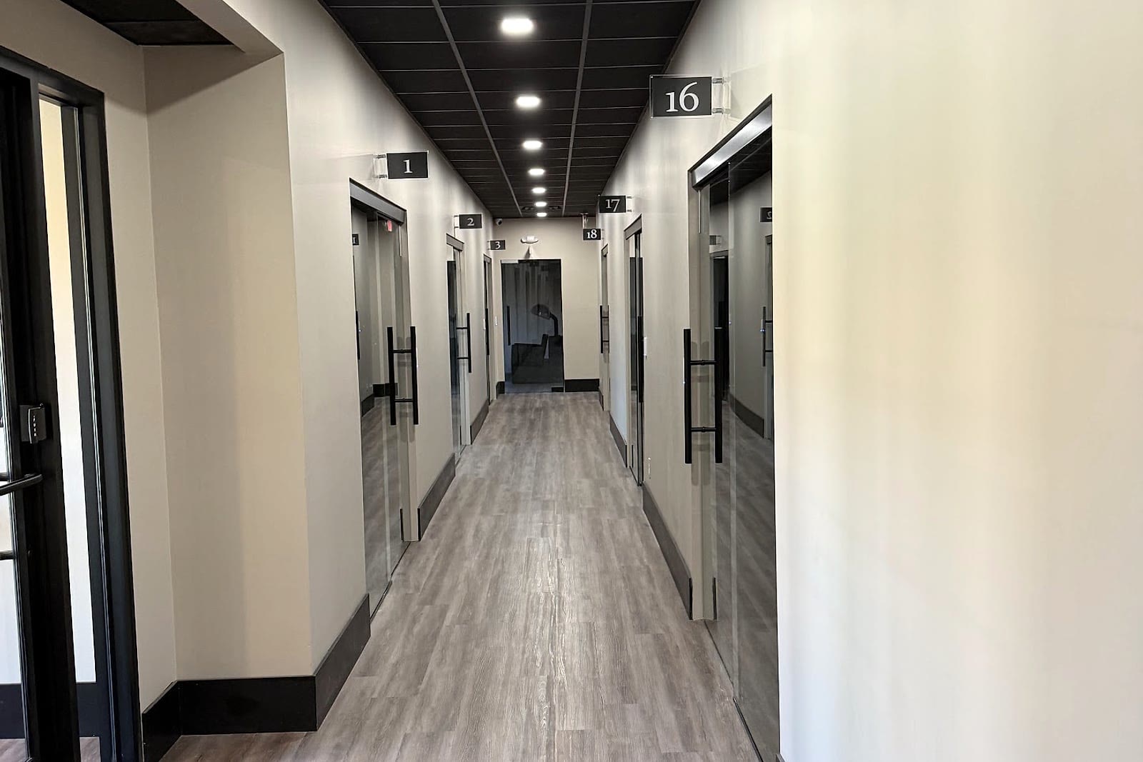 Finished salon suites hallway with access readers at individual glass doors.